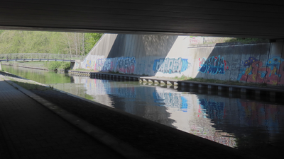 912734 Afbeelding van graffiti onder het Rhijnoordviaduct over de Leidsche Rijn te Utrecht, met op de achtergrond het ...